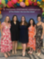 Five women smiling in front of colorful balloon arch with text "National Stuttering Association: If You Stutter, You Are Not Alone!"
