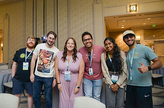 A diverse group of young adults smiling at a National Stuttering Association conference, wearing event lanyards.