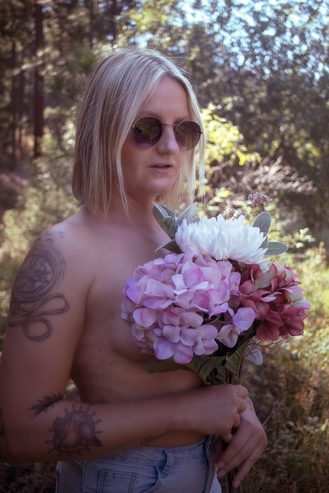 Lady holding a beautiful floral arrangement in front of a woodland forest.