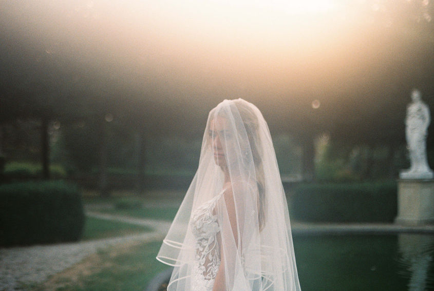 young bride in the setting sun captured through a foggy soft lens looking very vintage and analog vibes mysterious