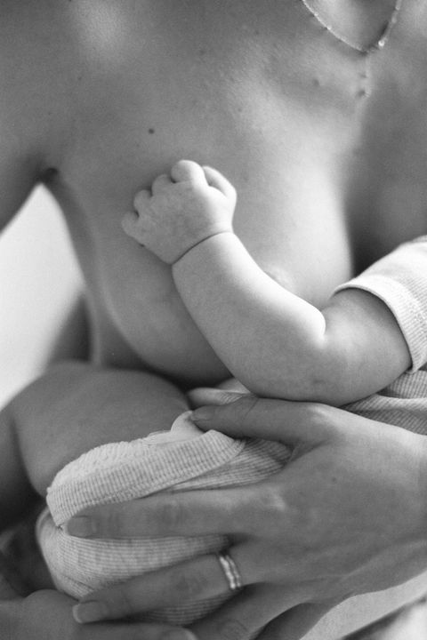 close up of a mother breastfeeding her baby tiny hand lies gently on her chest in black and white analog film
