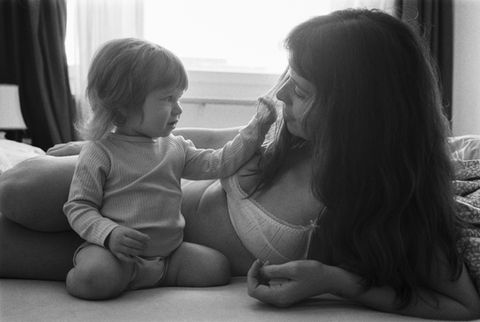 mother with her 1 year old daughter interacting sweetly in a homely setting on the bed. baby touches her hair and she's looking at her with gratitude