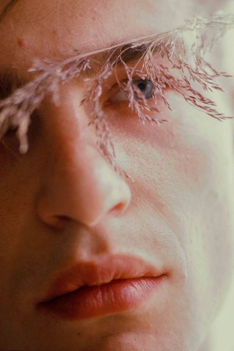 close up of a young mans face with expired fuji velvia dia film and a little fern