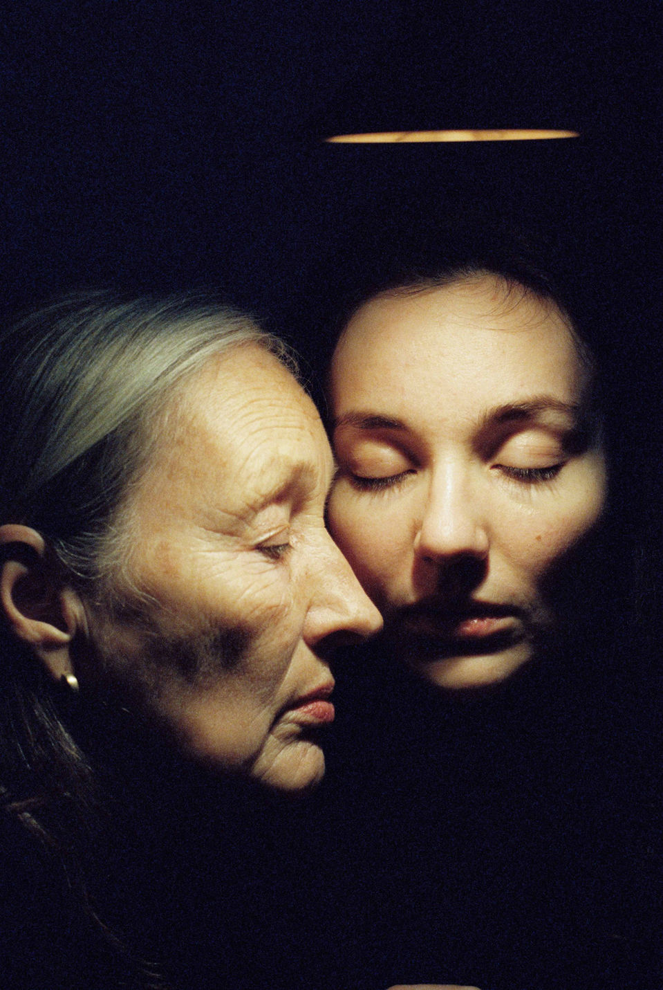 Mother and Daughter portrayed on Cinestill 800 T in a close up artistic way with eyes closed.