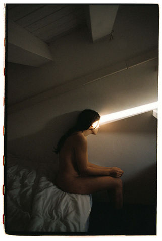 woman sitting in a dark room and just one single light stripe touches her face
