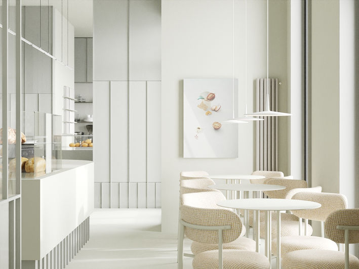 Minimalist cafe nterior with round tables, cushioned chairs, glass display case of bread, and modern hanging lights.