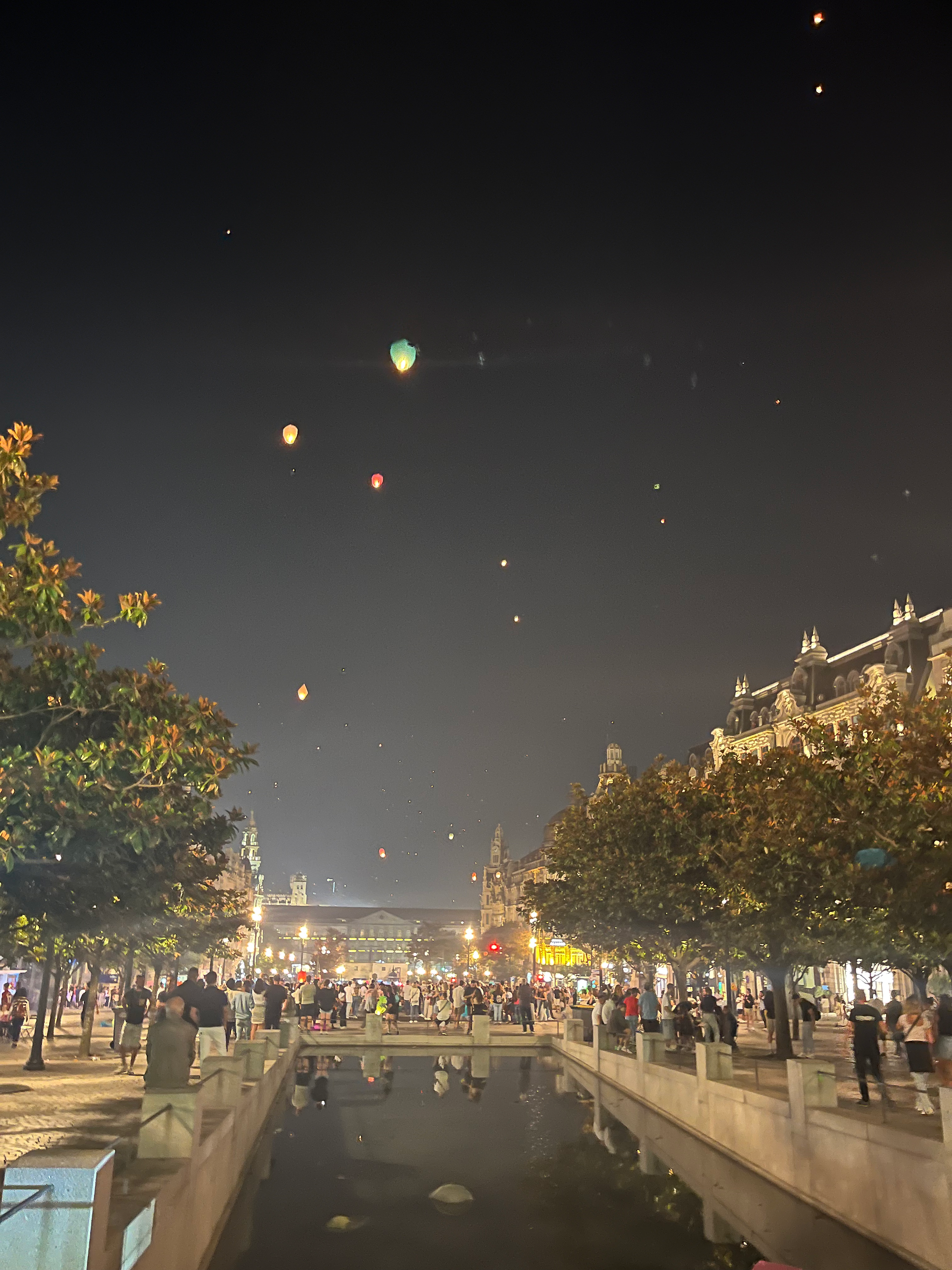 Colorful lanterns floating in the night sky over Porto, illuminating the cityscape during St. John’s Day celebrations.