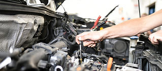 Person using screwdriver to adjust car engine component and wires