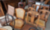 A collection of vintage wooden chairs, featuring ornate carvings and woven cane seats