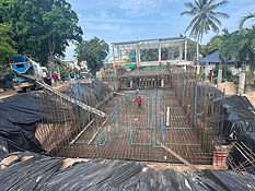 Construction site with metal framework, pipes, and workers