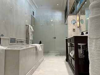 Luxurious bathroom with a marble tub, folded white towels, and a glass shower with frosted panels