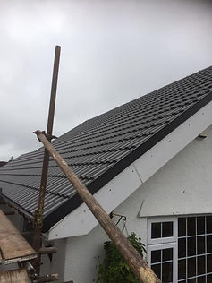 Steeply angled roof with grey metal tiles on a white house