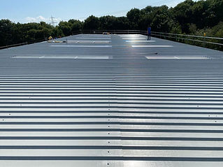 Person on large reflective metal warehouse roof