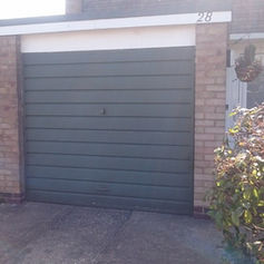 Closed green garage door on brick building labeled