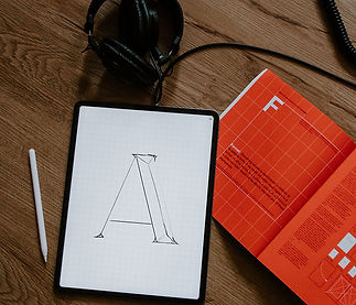 Tablet on a wooden table displays a sketch of the letter "A"
