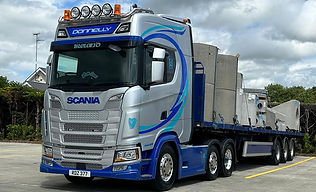 A sleek silver and blue semi-truck with decorative accents is parked under a cloudy sky