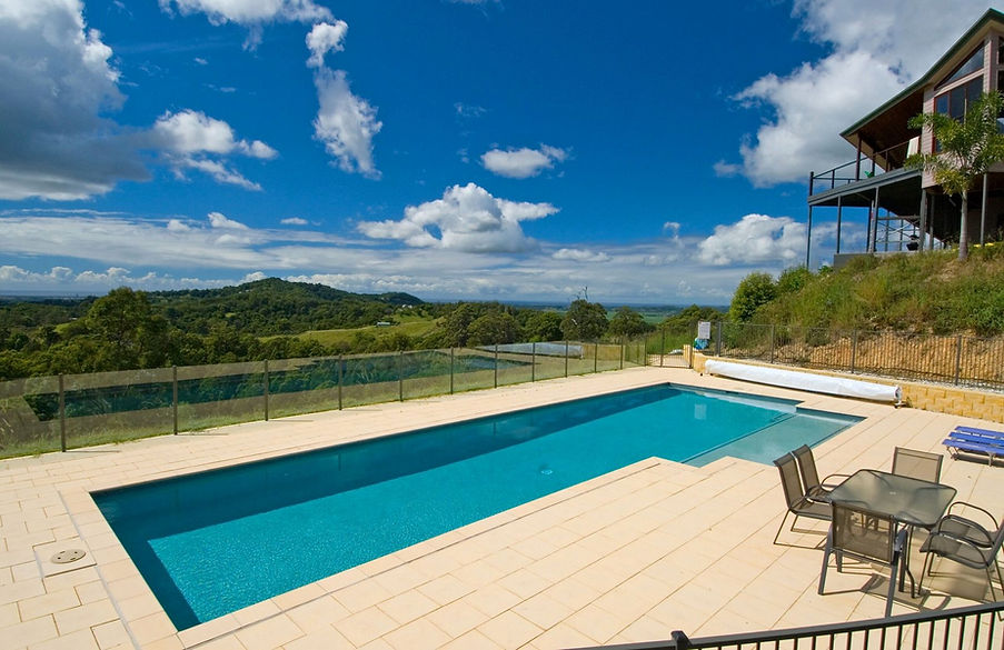 Rectangular pool on sunny patio with glass fence