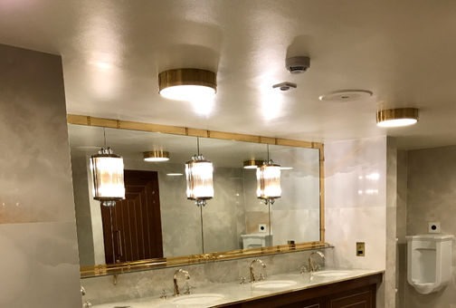 Luxurious restroom with marble sinks, large mirror, and golden accents