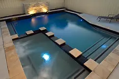 Blue-tiled pool at dusk with lights and stepping stones