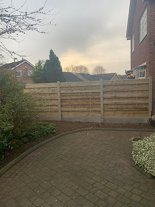 A brick house with a garden featuring bushes and a paved pathway