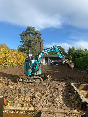 A small blue excavator works on a muddy yard