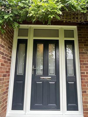 A white-framed black front door with glass panels, surrounded by red brick walls