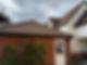 Small red brick outbuilding with a new terracotta tiled roof and a white door under an overcast sky