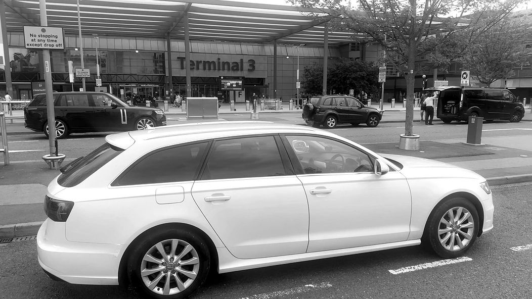 A white car is parked at an airport terminal