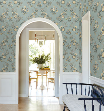 Golden yellow, beige, and taupe twining floral vines alternate with bouquets against a pale blue backdrop.