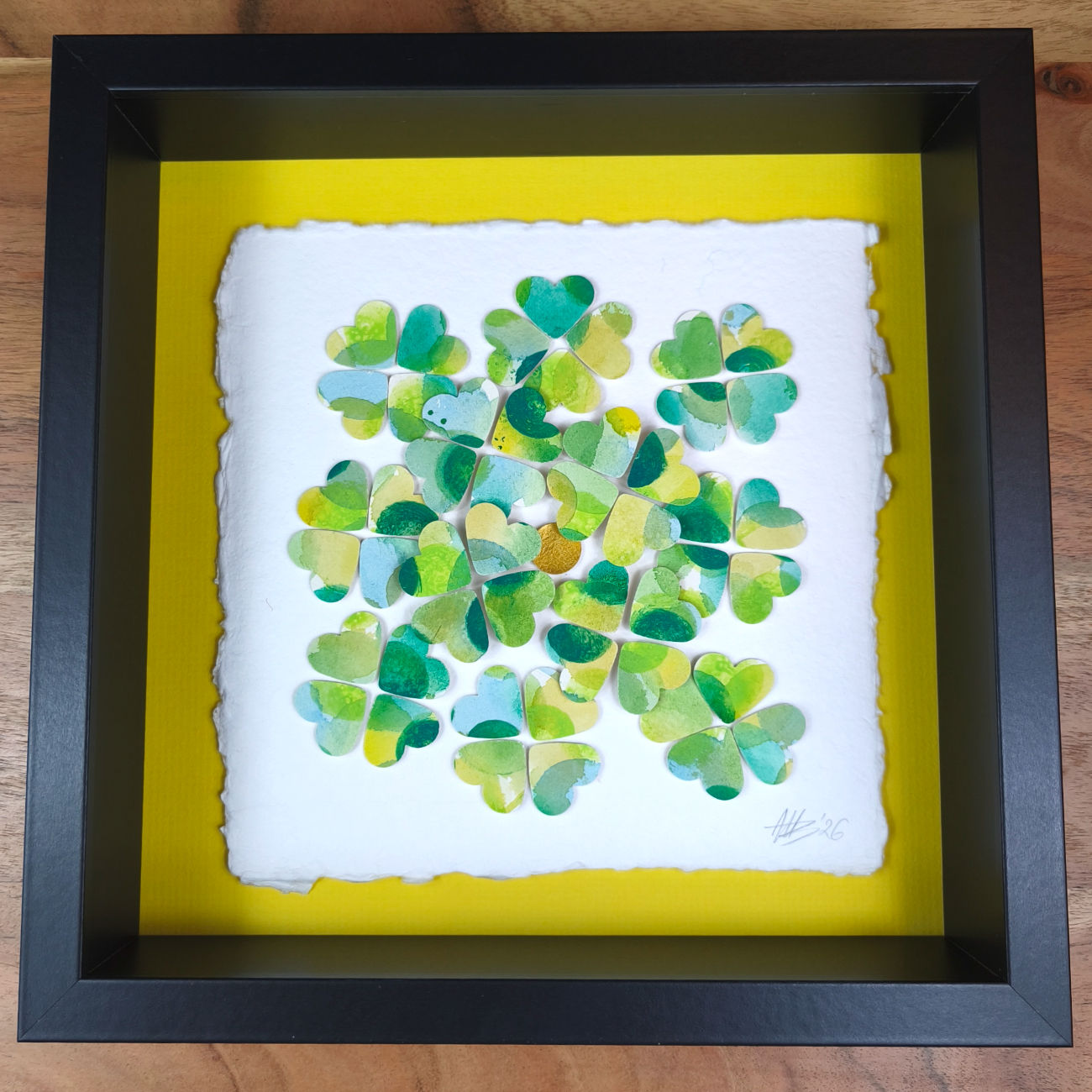 Vierblättrige Kleeblätter aus Papier geschnitten in verschiedenen Grüntönen, als 3D-Collage auf Büttenpapier