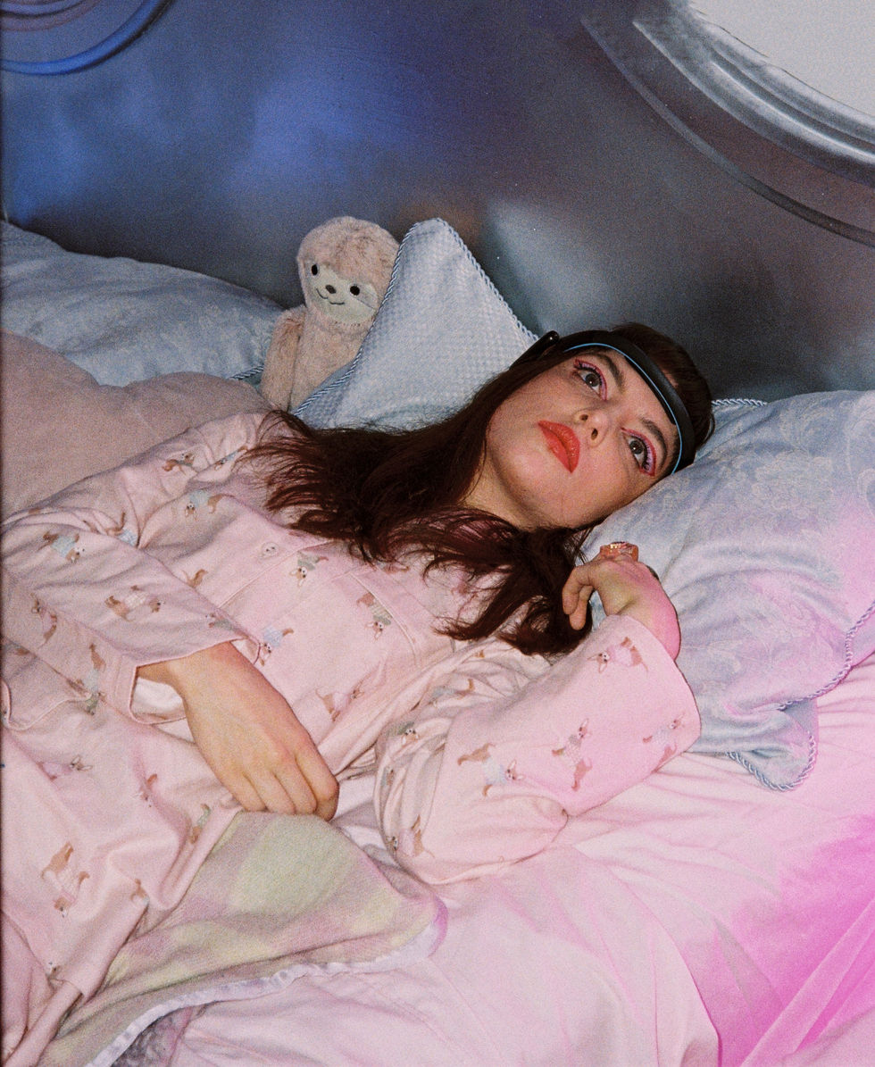 Young woman in pink pajamas lying in bed for Stream 2022