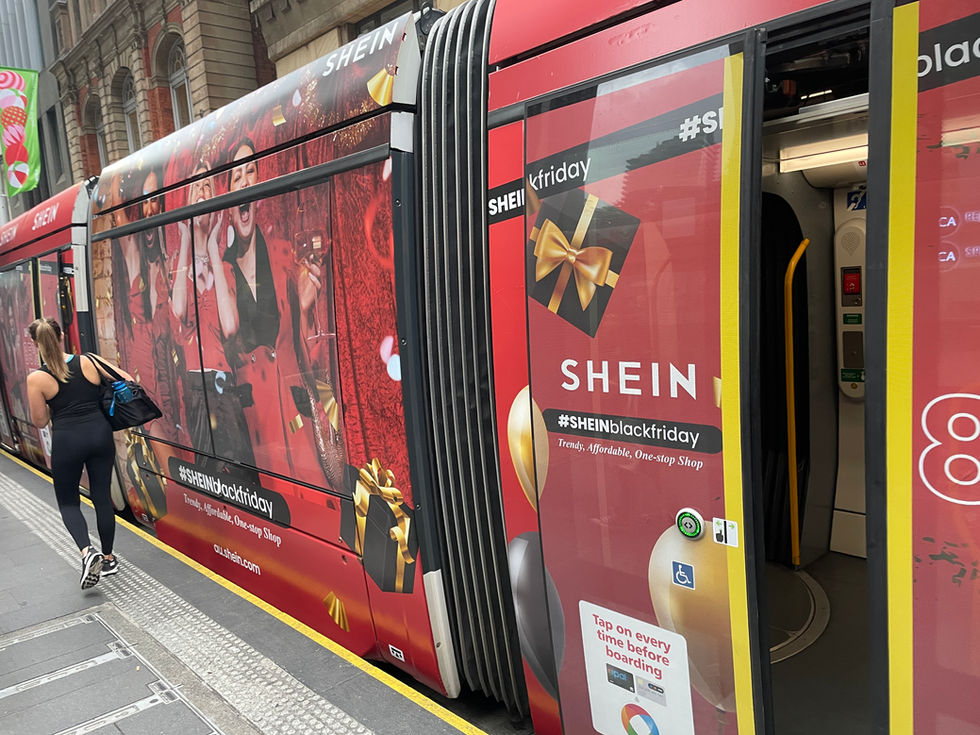 Red SHEIN Black Friday tram wrap in a city street.