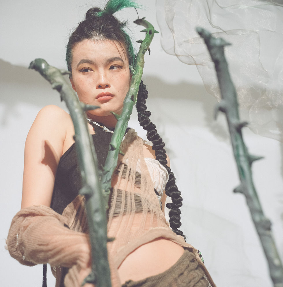 Woman with green hair and braided hair posing with thorns.