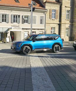 Blaues Auto auf Kopfsteinpflaster in Leibnitz, vor Laden, Stadtbild.