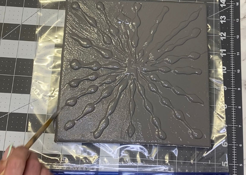 a canvas with a textured pattern made from hot glue being painted