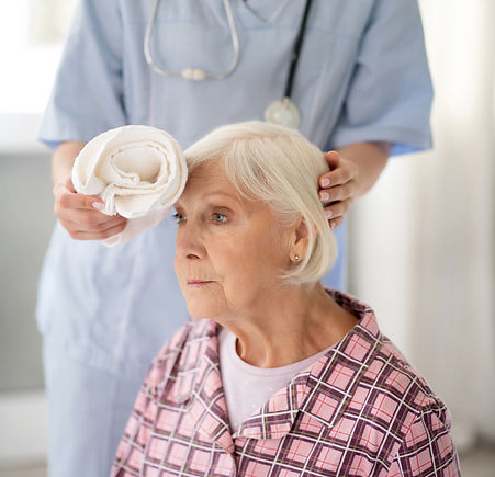 caring-nurse-putting-cold-towel-to-head-of-aged-wo-2021-09-03-20-25-49-utc.jpg