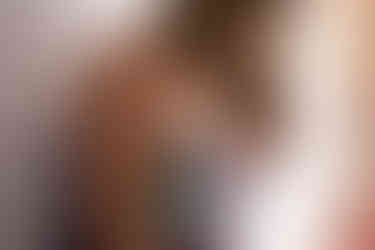 Close up photograph of woman in purple lingerie layered with iridescent body jewelry layered over it.