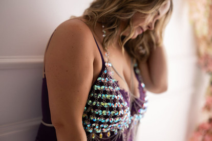 Close up photograph of woman in purple lingerie layered with iridescent body jewelry layered over it.