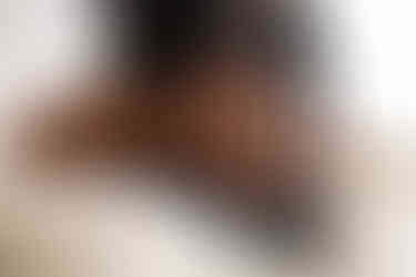 Close up boudoir photo of a woman's butt. She's wearing heels and her hands are holding on the stiletto heels. 