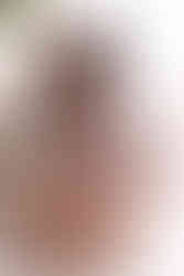 Boudoir photo of woman in blue lineage kneeling in front of large gold framed mirror. Her face is looking down and she seems relaxed.