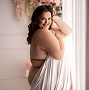 plus size woman boudoir in sheets by window