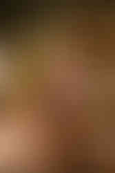 Boudoir portrait of woman in black lingerie posing next to table filled with candles.