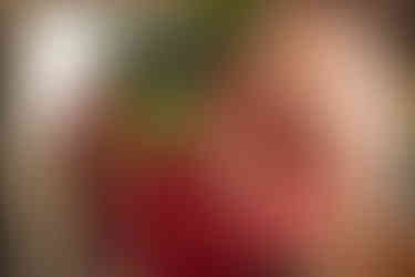 Boudoir photo of a woman's torso unfocused, with the camera focusing on her reflection in a large gold framed mirror in the background.