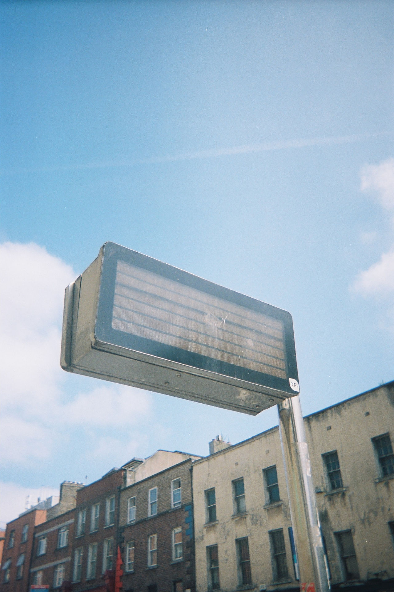 Film photography of a Dublin bus stop sign against a blue sky