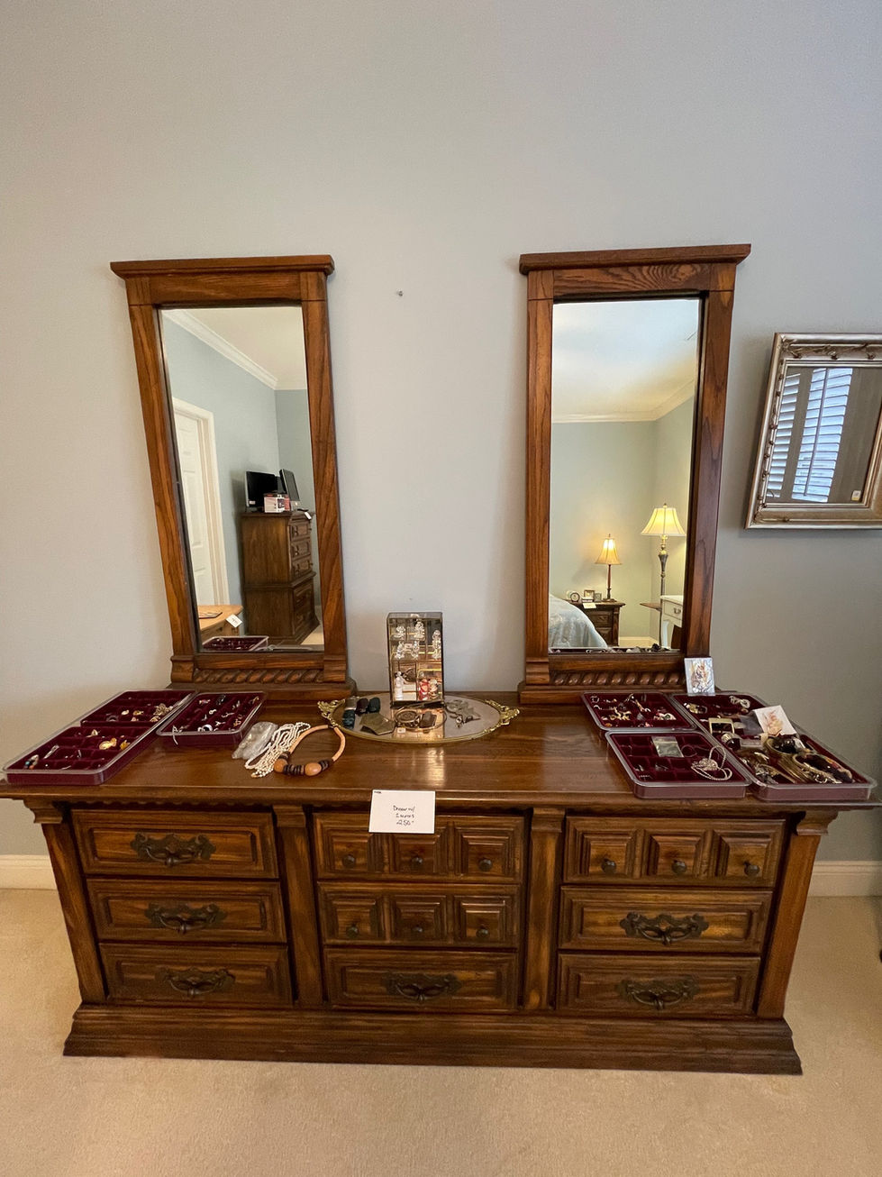 a dresser with two mirrors and trays of jewelry on it