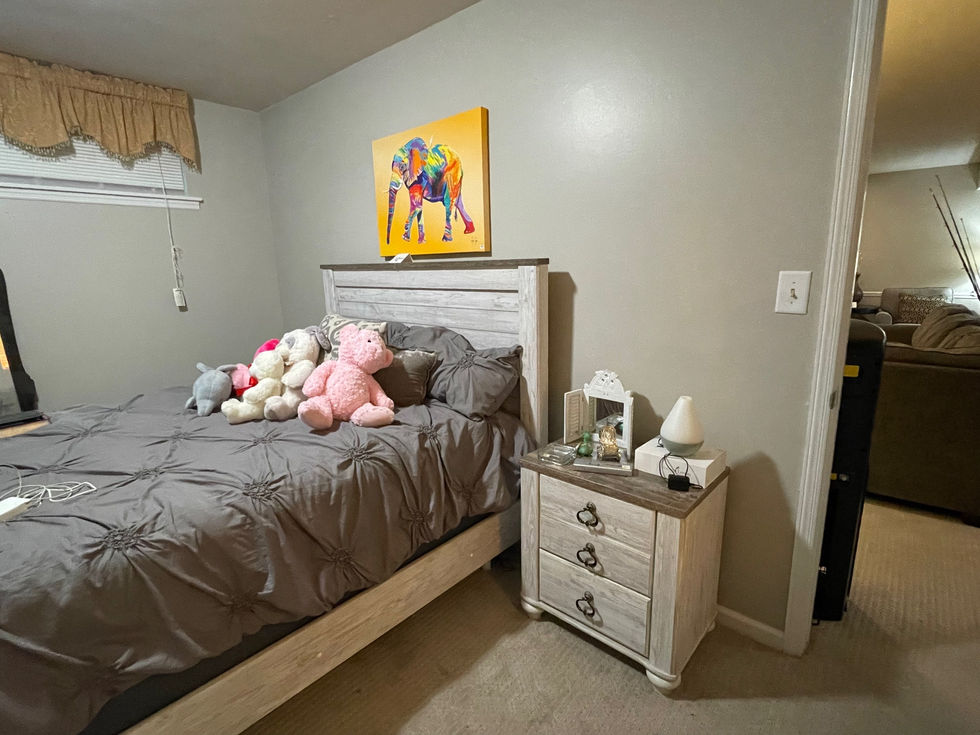 a bedroom with a bed a nightstand and a painting of an elephant on the wall