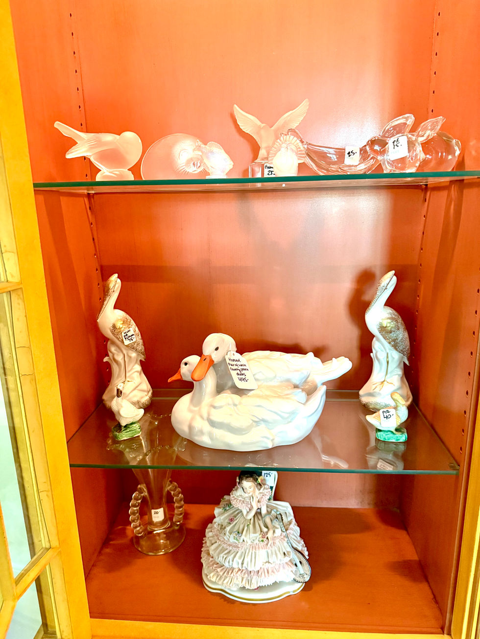 Glass figurines displayed on shelves against a red background.