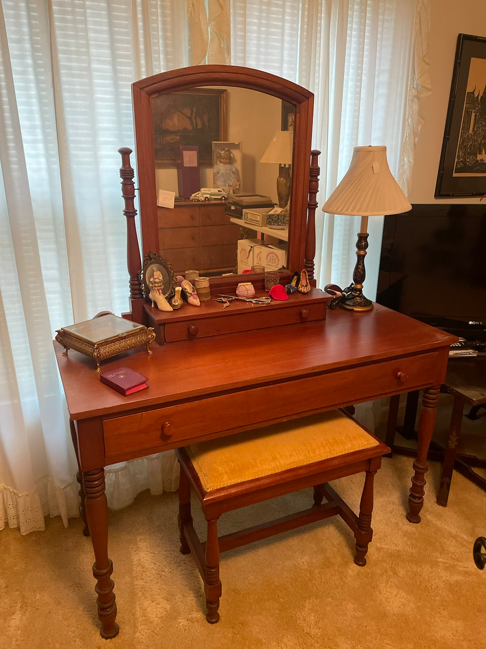 a wooden vanity with a mirror and a stool