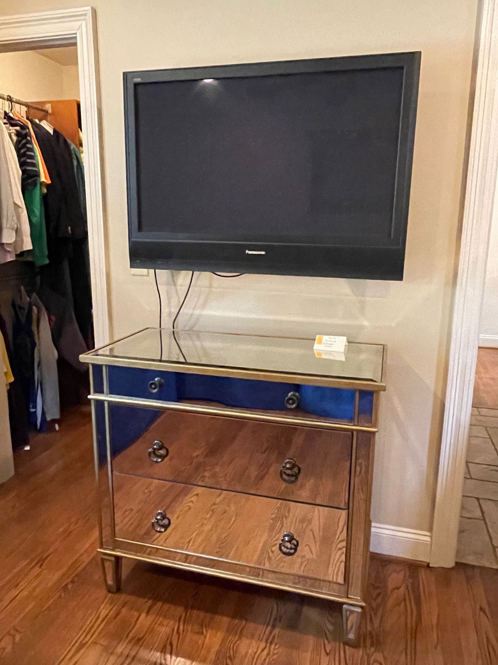 a panasonic television is mounted above a mirrored dresser