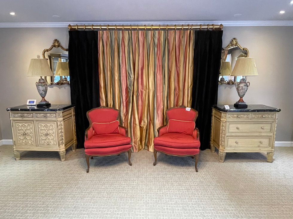 two red chairs are sitting in front of a black curtain